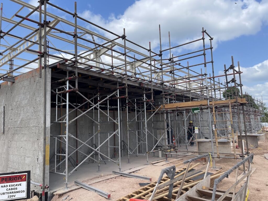 Canteiro de obras da PCP Barbosa em Moju mostrando sistema complexo de escoramento metálico e andaimes tubulares para sustentação de laje e vigas de concreto.