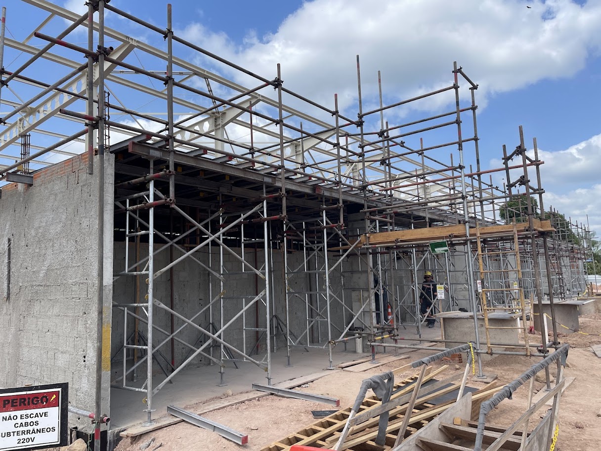 Canteiro de obras da PCP Barbosa em Moju mostrando sistema complexo de escoramento metálico e andaimes tubulares para sustentação de laje e vigas de concreto.
