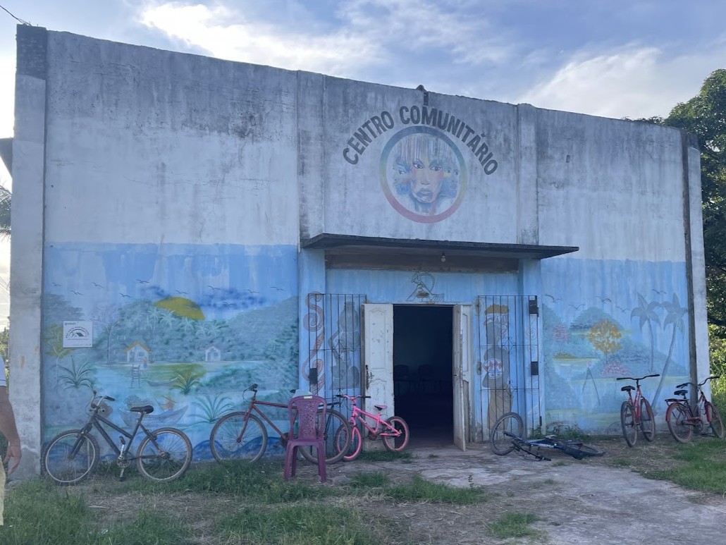 Fachada do Centro Comunitário Rio em Barcarena antes da reforma, com pintura artística azul desgastada e marcas de infiltração.