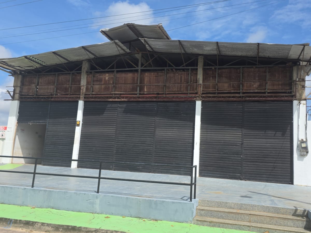Vista frontal de galpão comercial com três grandes portas de aço pretas, colunas de concreto brancas e telhado metálico de zinco com lanternim para ventilação em Barcarena.