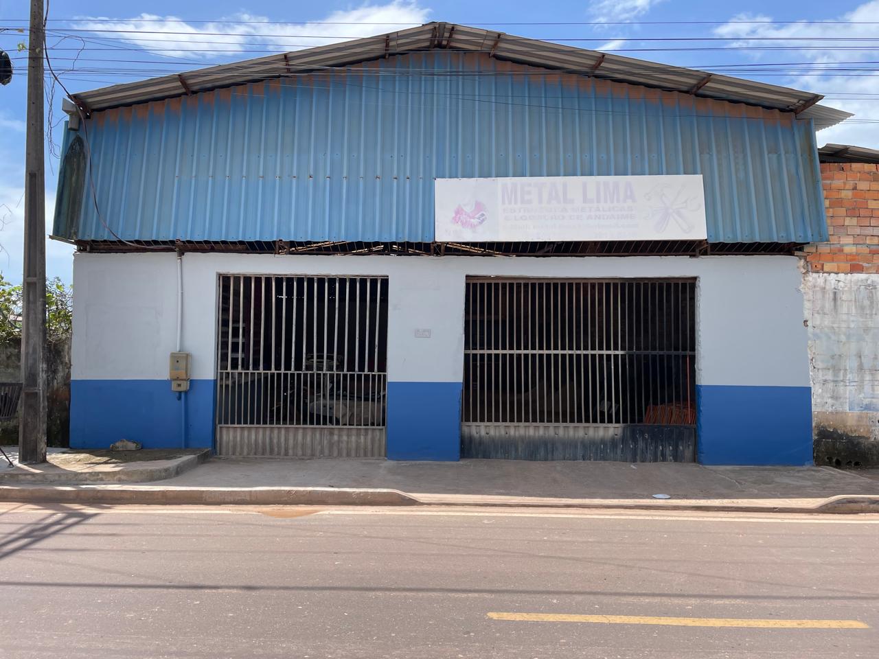 Fachada da oficina Metal Lima em Barcarena, com galpão de estrutura metálica azul, portões de grade e placa de identificação na entrada.