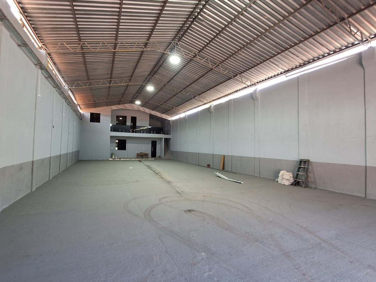 Vista interna panorâmica de galpão comercial finalizado em Barcarena, com piso industrial cinza, paredes em dois tons de cinza e bloco administrativo de dois pavimentos ao fundo.