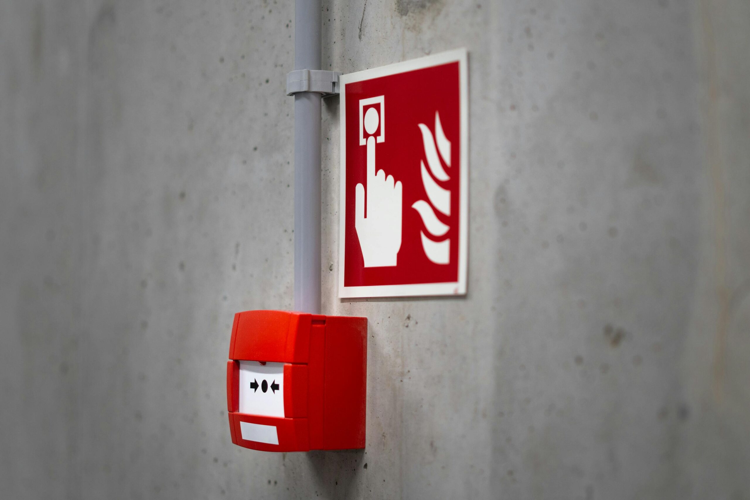 Artigos Red fire alarm button and sign on a concrete wall for emergency safety indoors.